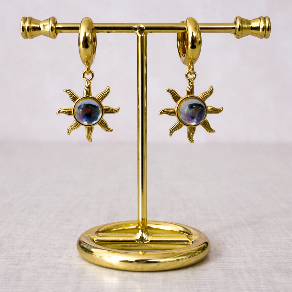 Huggies de chapa de oro dorada con dije de sol y detalles azul tipo ojo