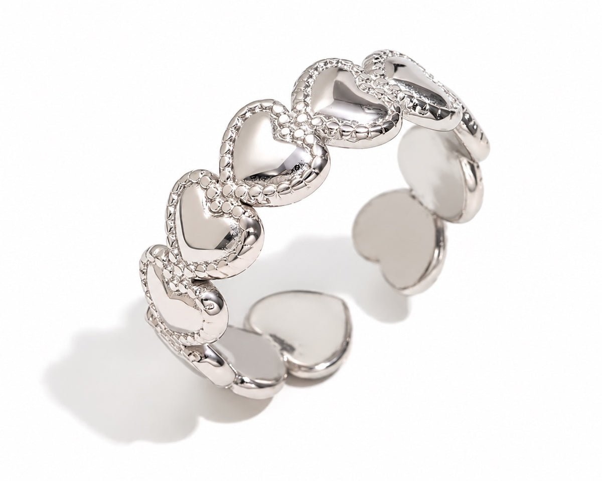 Anillo Amor Plateado ajustable de acero inoxidable 316L con corazones y bordes de pequeñas bolitas.