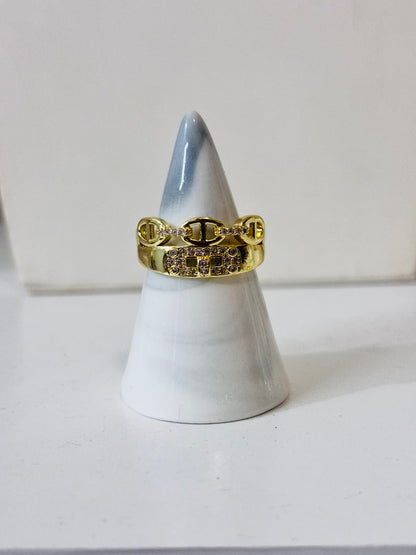 Anillo con piedras decorativas y detalles dorados en acero inoxidable 316L, diseño elegante y brillante para joyería de mayoreo.