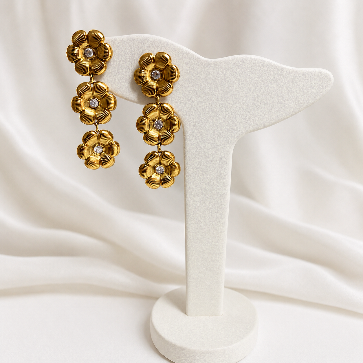 Arete Triple dorado de acero inoxidable 316L con tres flores y detalle brillante central.