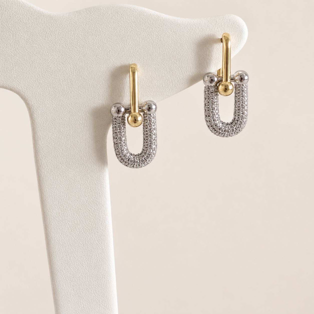 Arete Tiffany bicolor en chapa de oro de 18K. Diseño femenino, moderno y fácil de combinar para inventarios de joyería de mayoreo.