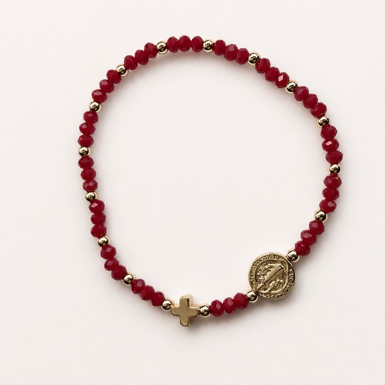 Pulsera religiosa con piedras rojas y detalles en chapa de oro 18K, de diseño femenino y significativo.
